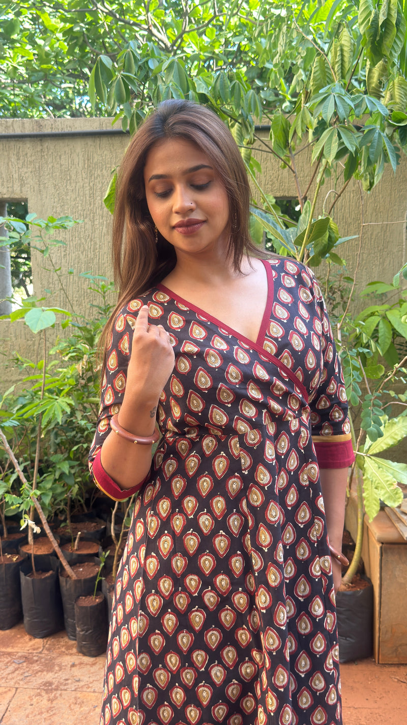 Close-up of the red and cream leaf motifs printed across the black cotton fabric of the long dress.