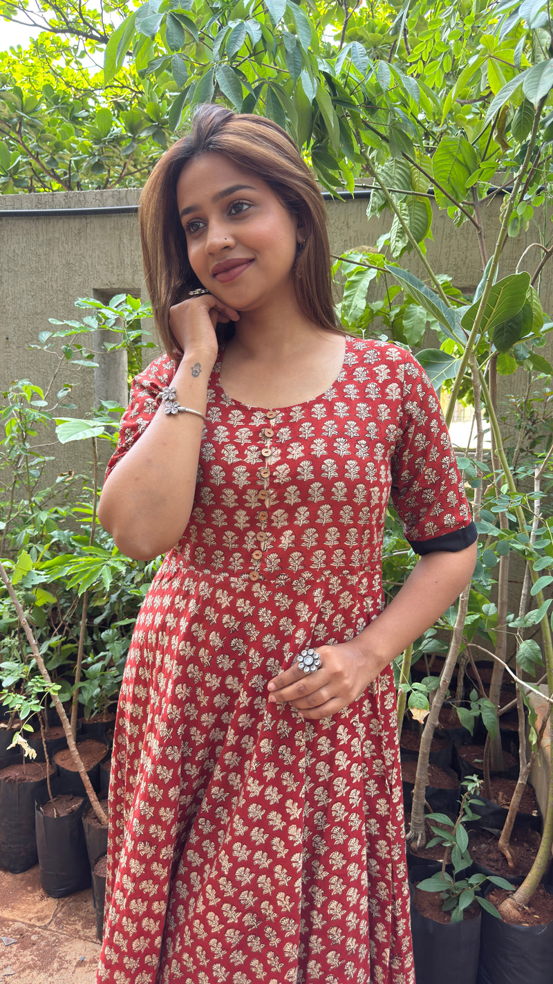 Front view of red block-print long dress with V-neckline and elbow sleeves trimmed in black