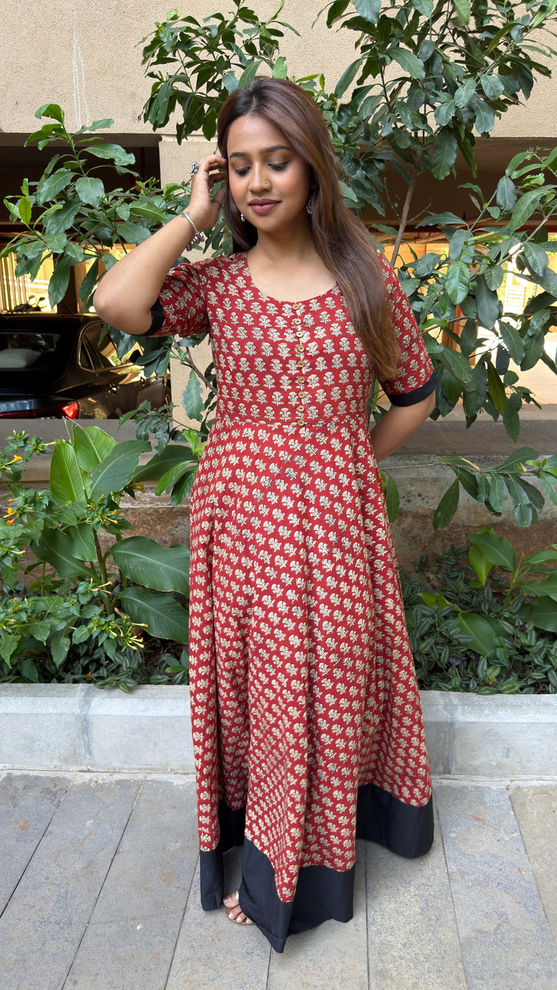 Three-quarter view of red handloom cotton dress showing A-line silhouette and black hem panel