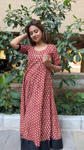 Side view of red long dress with small white floral motifs and elbow sleeve cuff in black