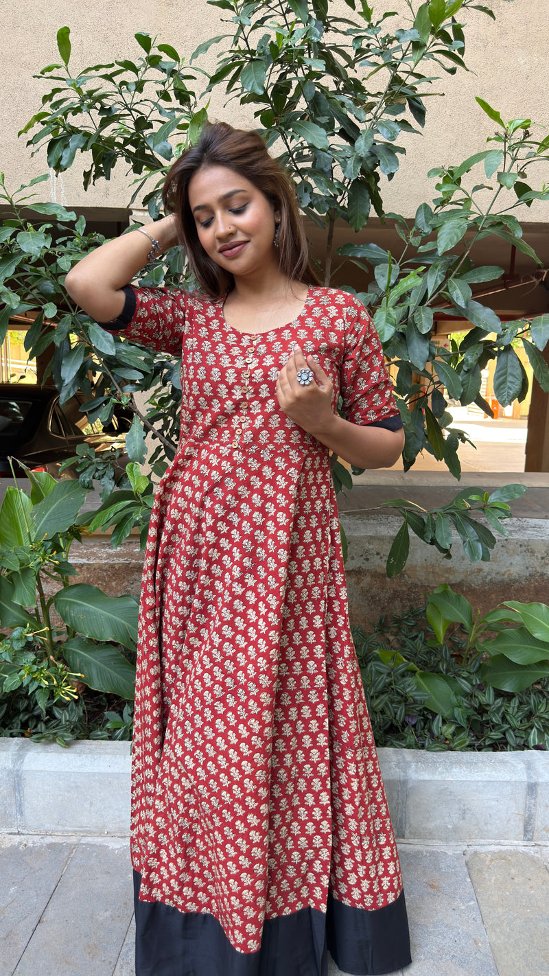 Side view of red long dress with small white floral motifs and elbow sleeve cuff in black