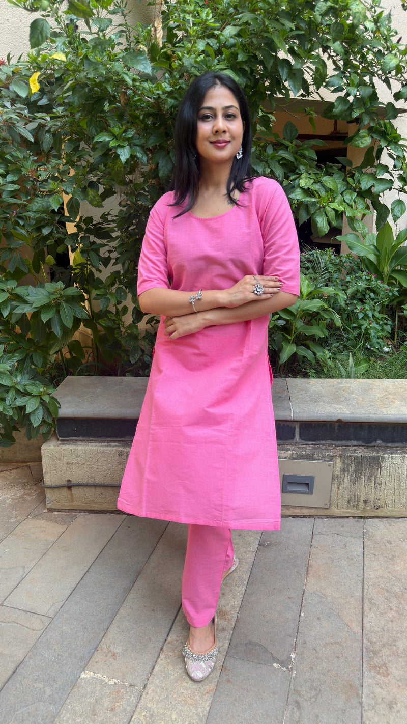 Three quarter length view of the elbow sleeve pink cotton kurta set worn with silver earrings.