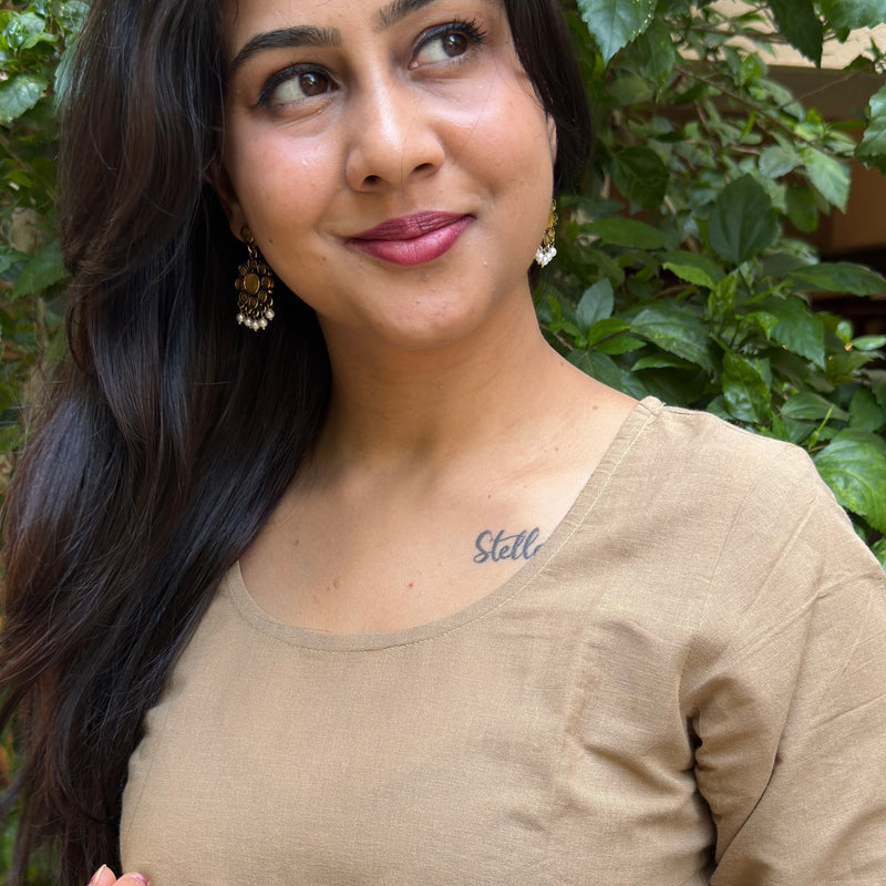 A woman wearing a regular fit beige cotton kurta set with a soft drape and simple silhouette.