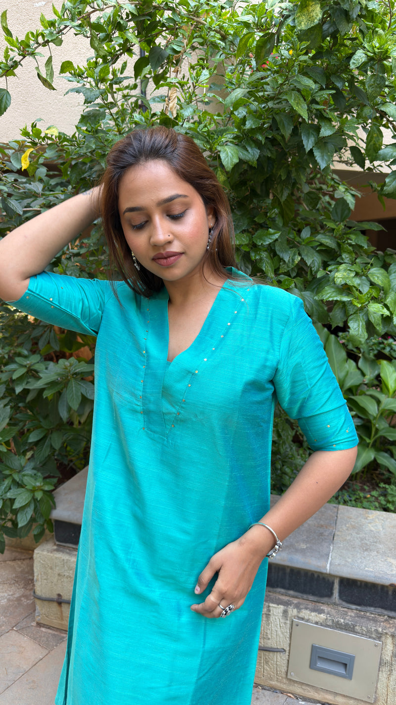 Full body view of a woman showcasing the relaxed palazzo trousers paired with a teal slub silk kurta.