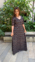 Three-quarter view of black block print wrap dress with A-line drape