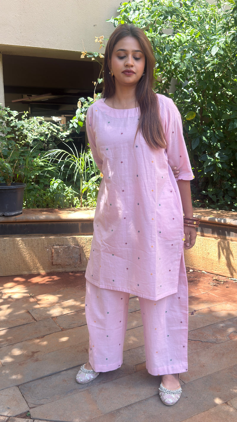 Lower body view of the light pink cotton trousers paired with embellished flat footwear.