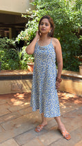 Model walking in blue floral block print calf-length dress in courtyard