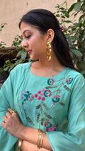 Detail of coral and green floral embroidery on mint art silk