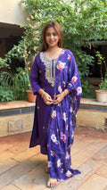 Model in deep purple art silk kurta with mirror work embroidered yoke and floral printed dupatta in cream and coral