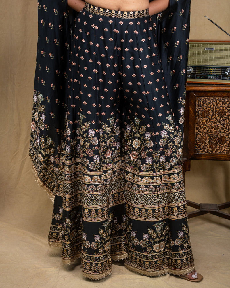 Standing view of a three-piece black floral modal cape set with flared leg pants