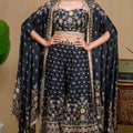 Model wearing a black floral modal cape set standing next to a vintage carved table