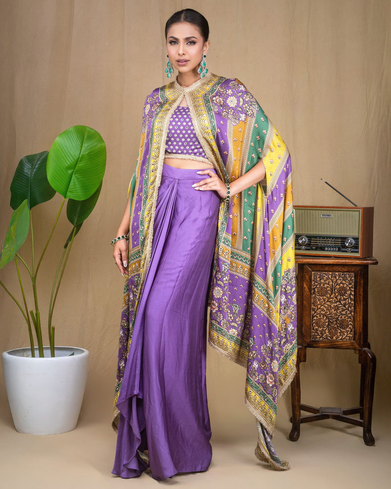 Full-length front view of model in purple modal draped skirt with embroidered blouse and cape set.