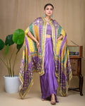 Side view of model wearing a purple draped modal skirt set with a sweeping patterned cape jacket.