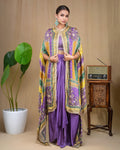 Back view showing the flowing printed cape jacket in purple, yellow, and green tones over draped skirt.
