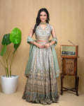 Full length view of a woman in a sage green hand embroidered modal lehenga set with dupatta.