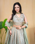 Model styling the sage green embroidered modal lehenga set with green choker jewelry.