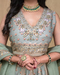 Close up of the embroidered hem and fluid drape of the sage green modal lehenga skirt.