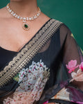 Close-up of the pleats on a black organza saree adorned with pink floral motifs
