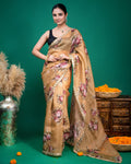 Full length view of model wearing a beige floral organza saree with a black sleeveless blouse.