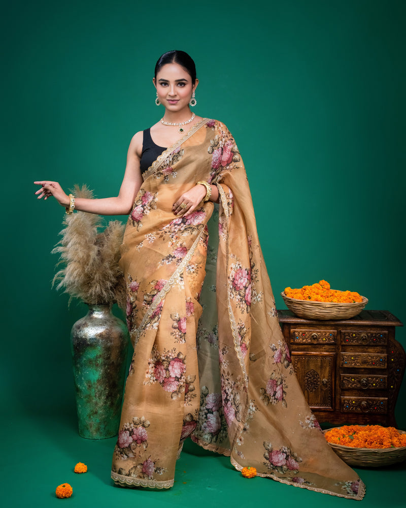Close up shot of beige floral organza saree showing pink rose prints and embroidered lace border.