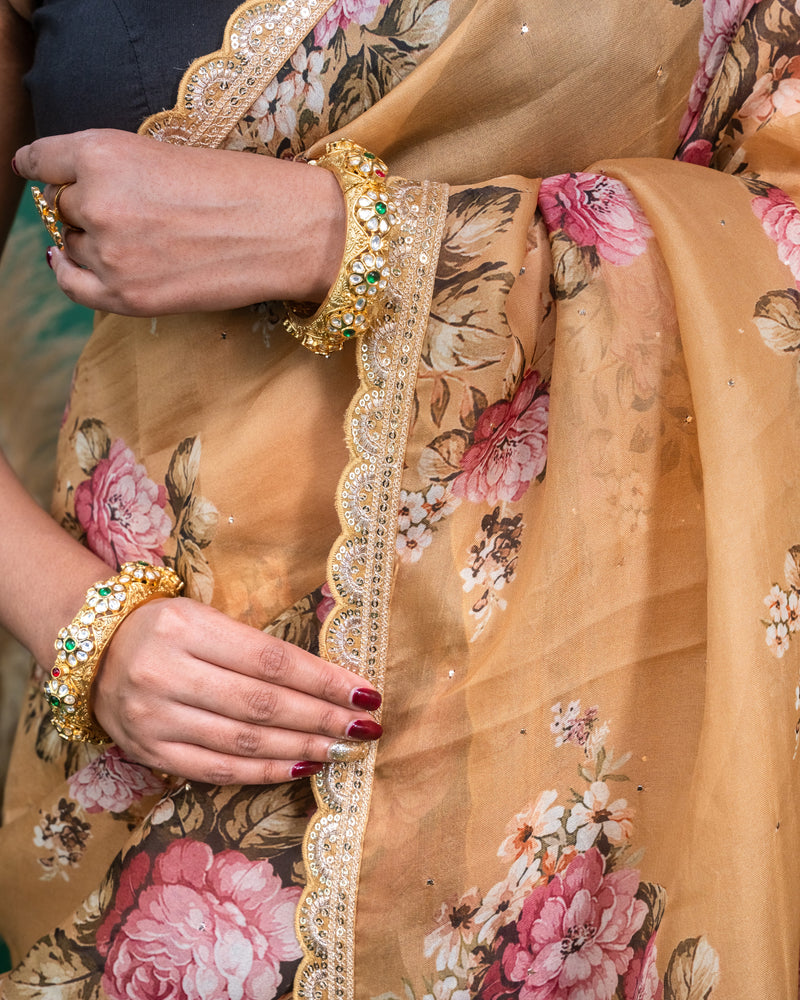 Mid section detail of beige organza saree highlighting the delicate rose print and pleats.